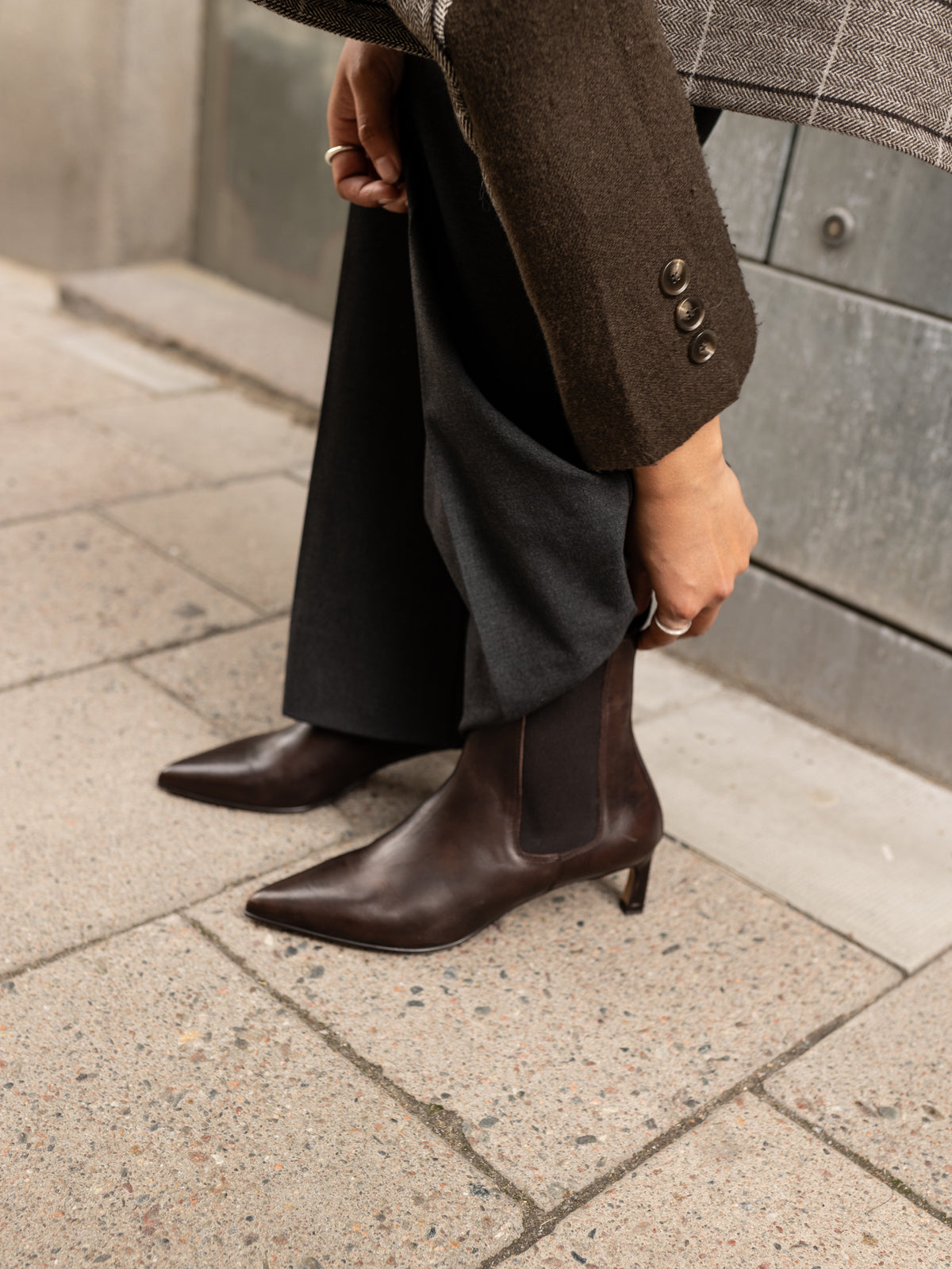 Person wearing brown ankle boots on a sidewalk