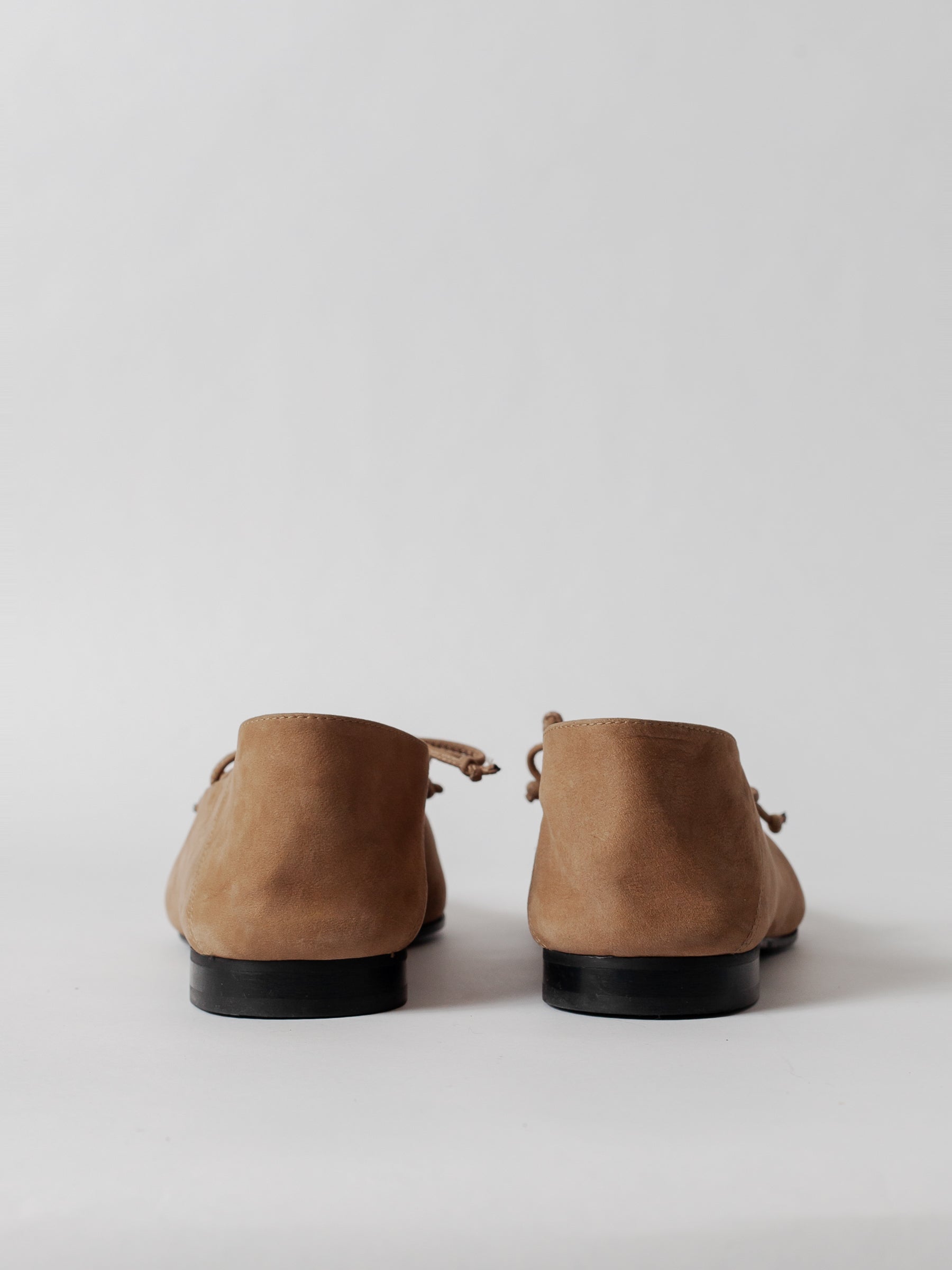 Pair of brown suede shoes on a light gray background
