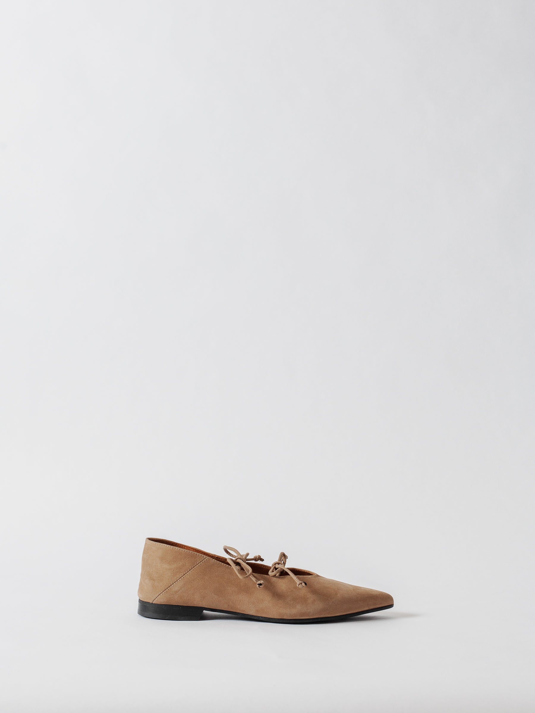 Tan suede flat shoe on a light gray background