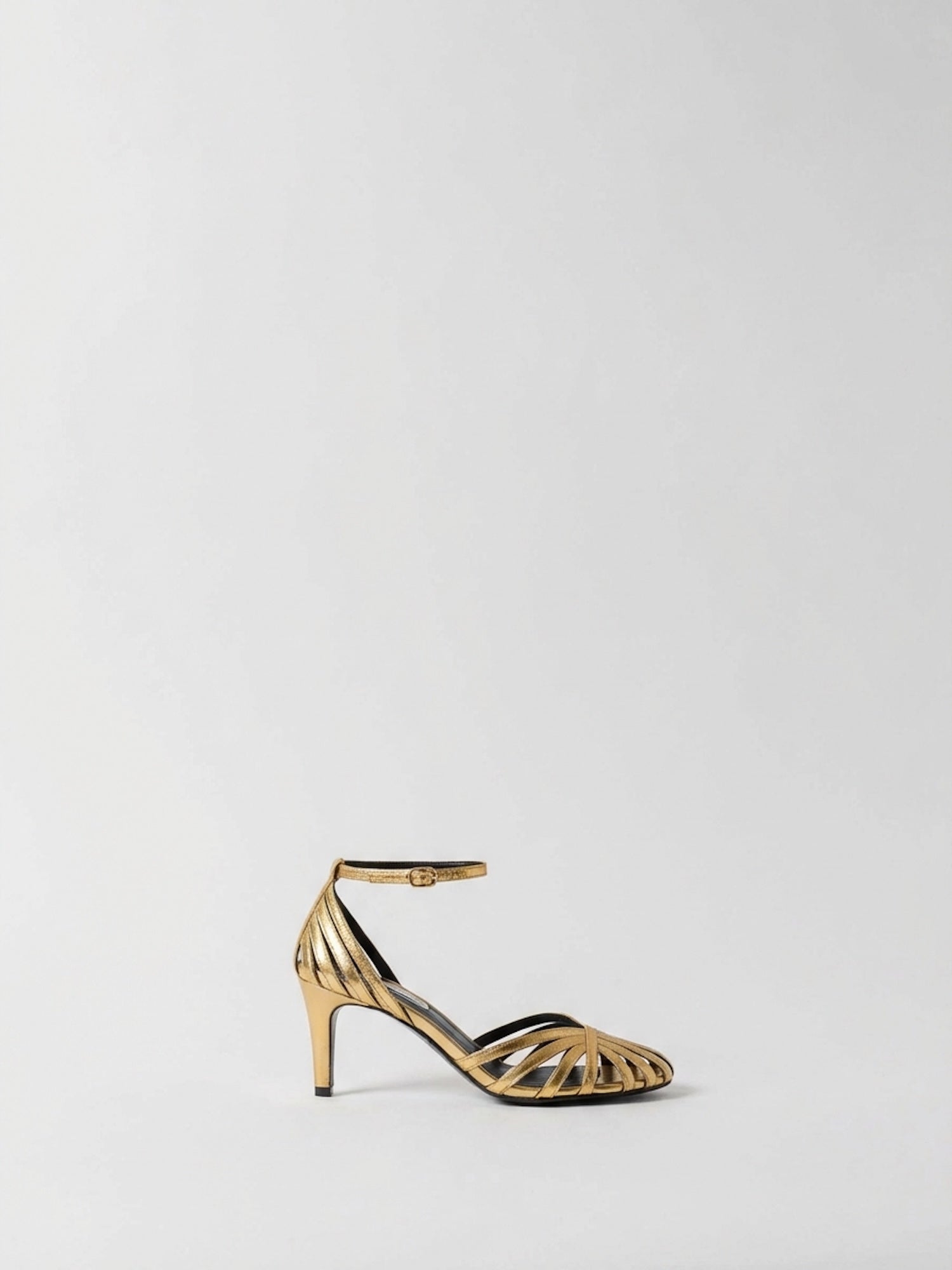 Gold high-heeled shoe on a light gray background