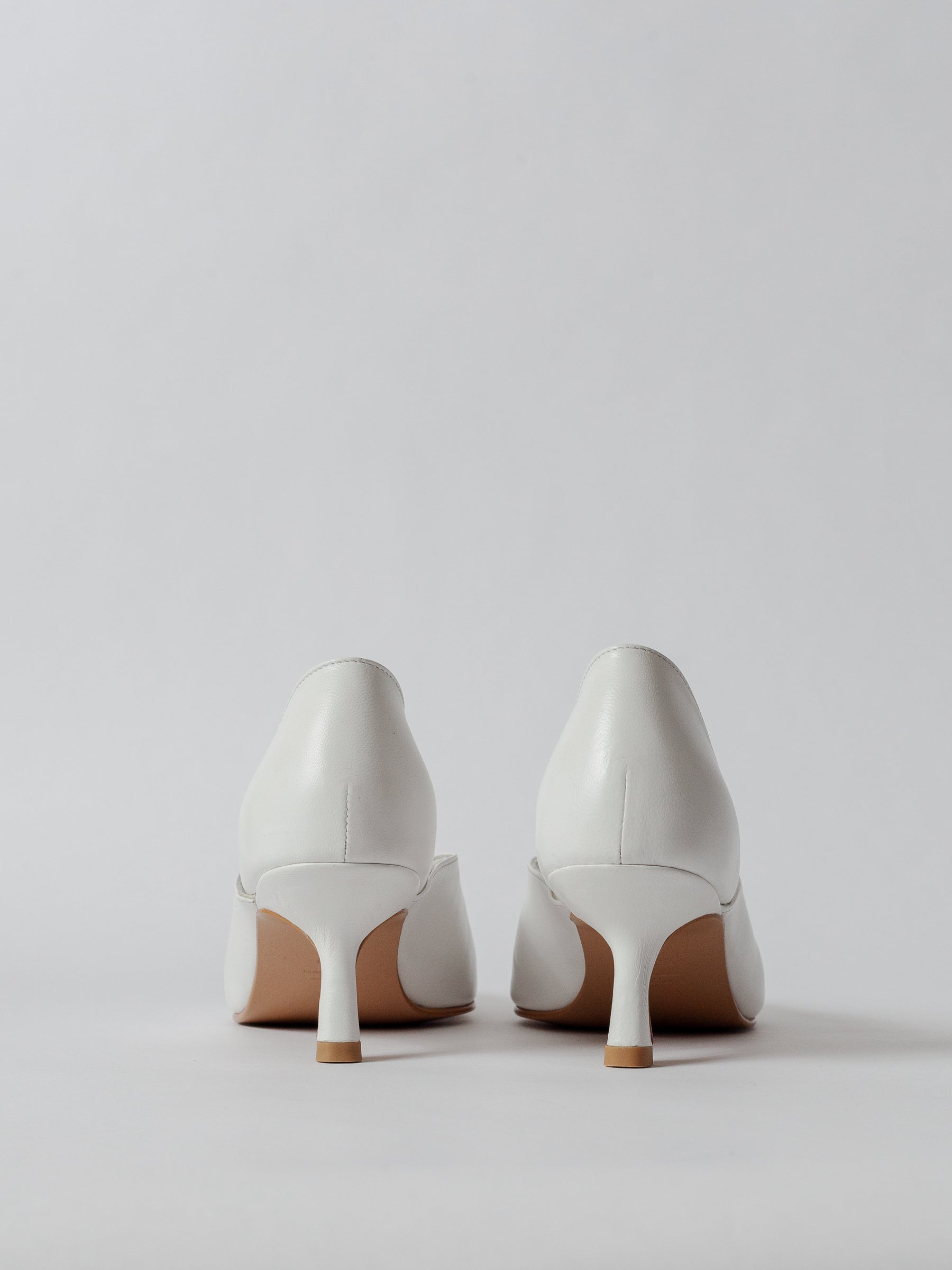 White high-heeled shoes on a light gray background