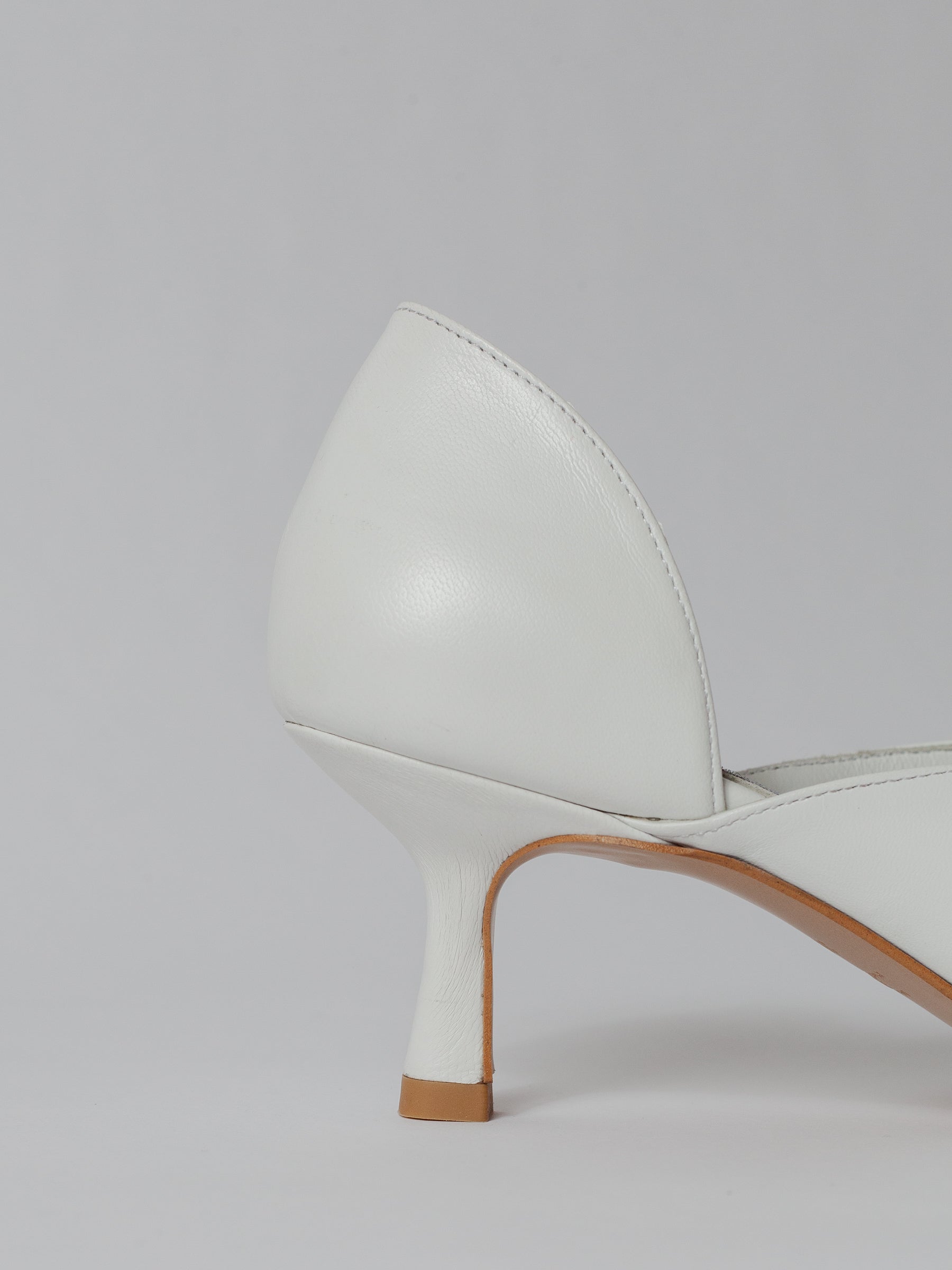 White high-heeled shoes on a light gray background