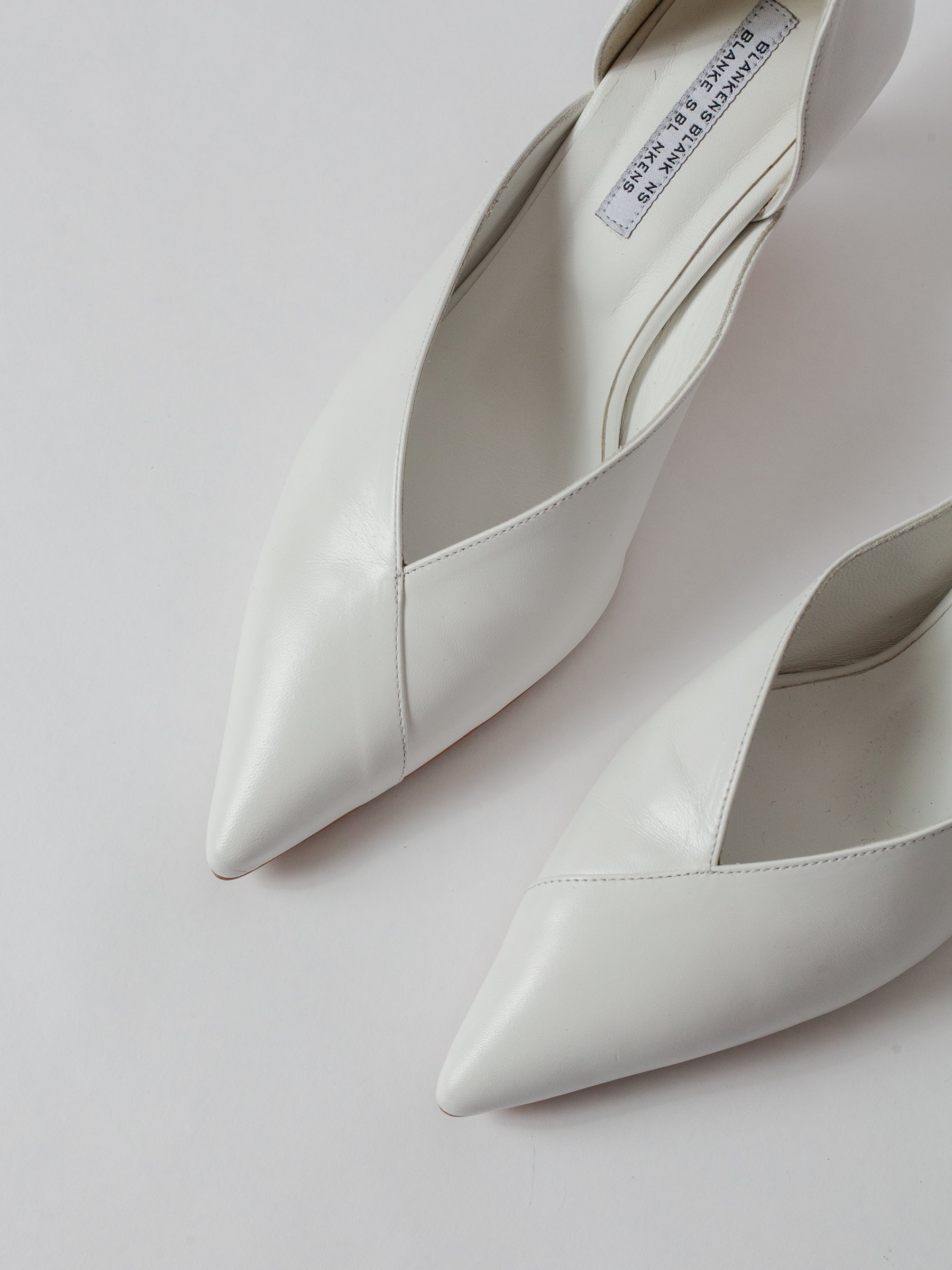 White pointed-toe shoes on a light gray background