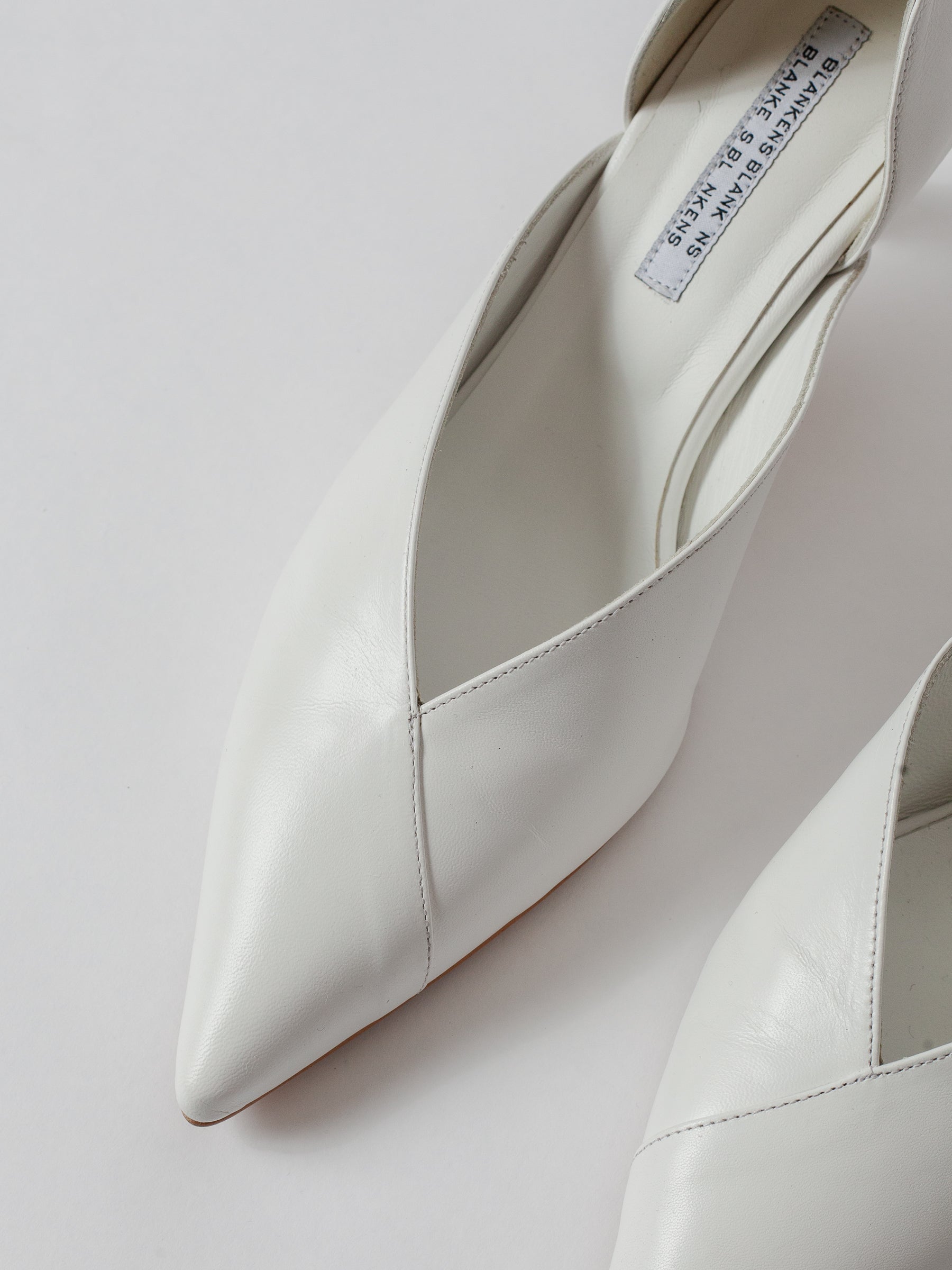 White pointed-toe shoes on a light gray background