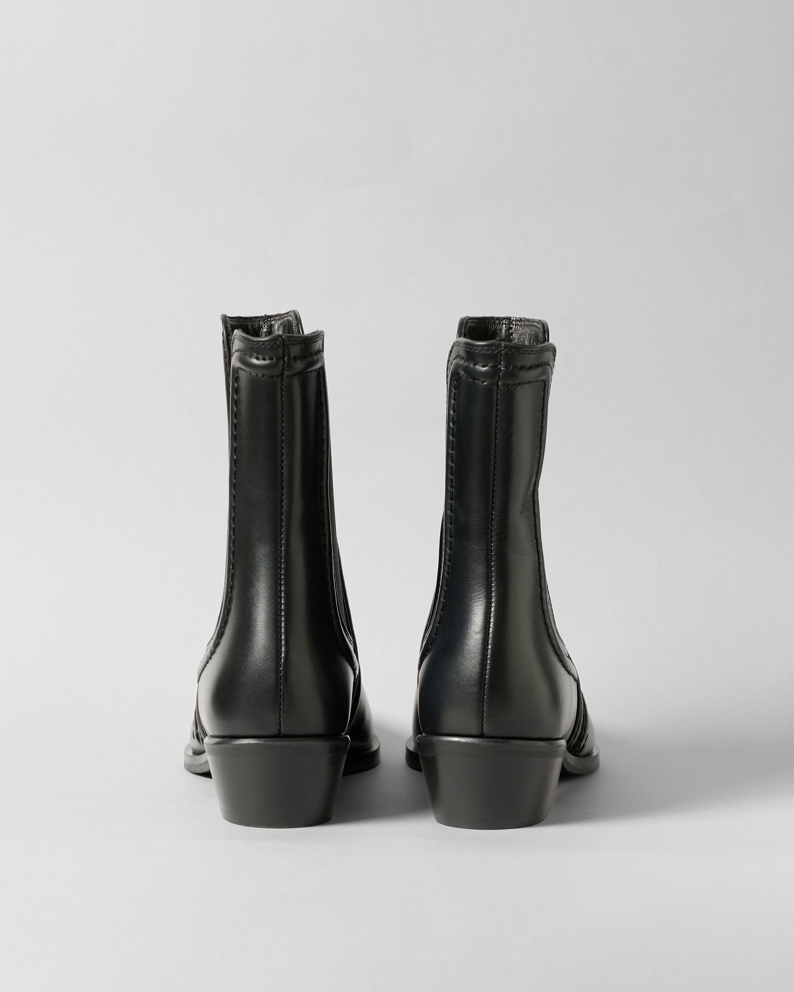 Pair of black leather boots on a light gray background