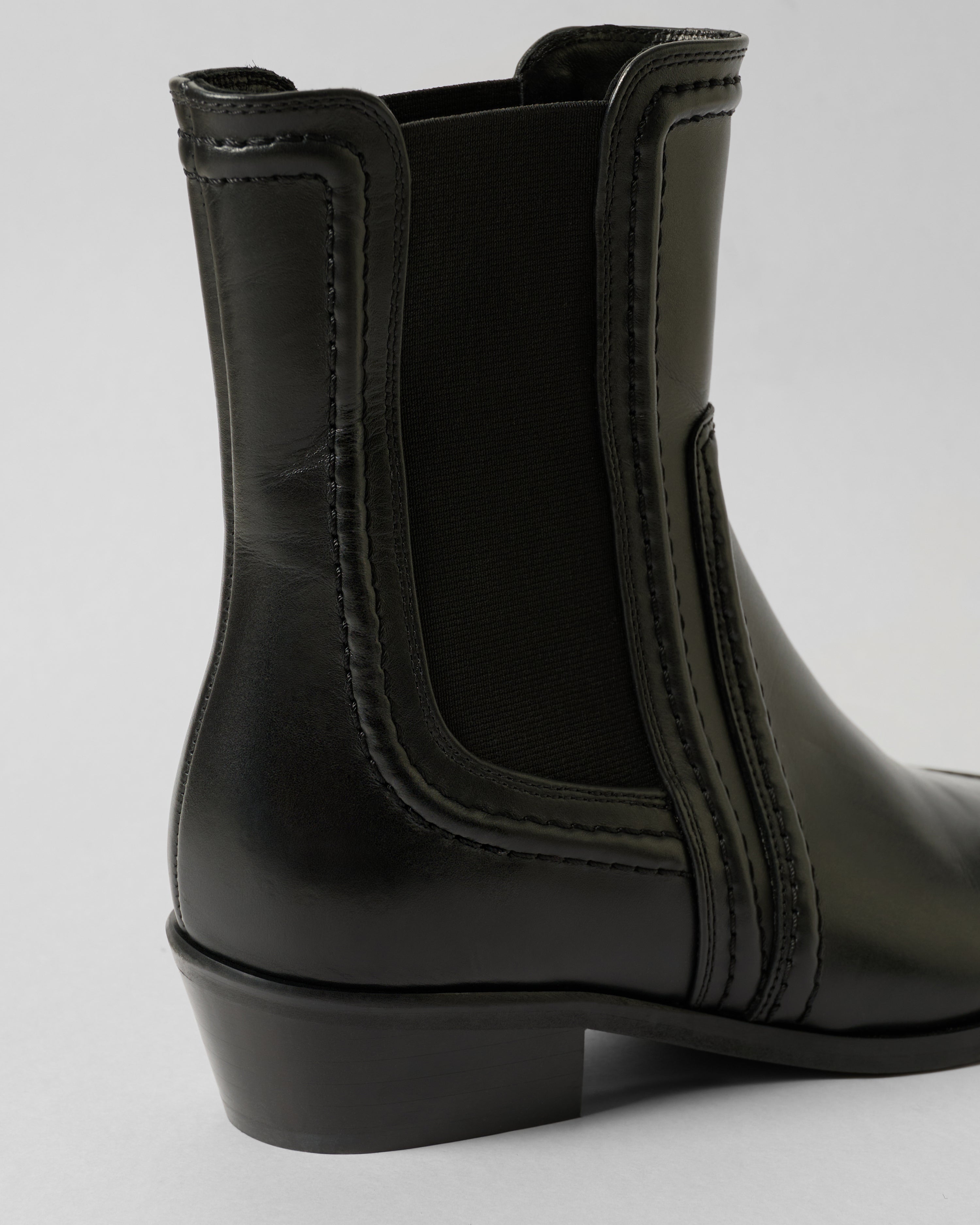 Black leather boot on a light gray background