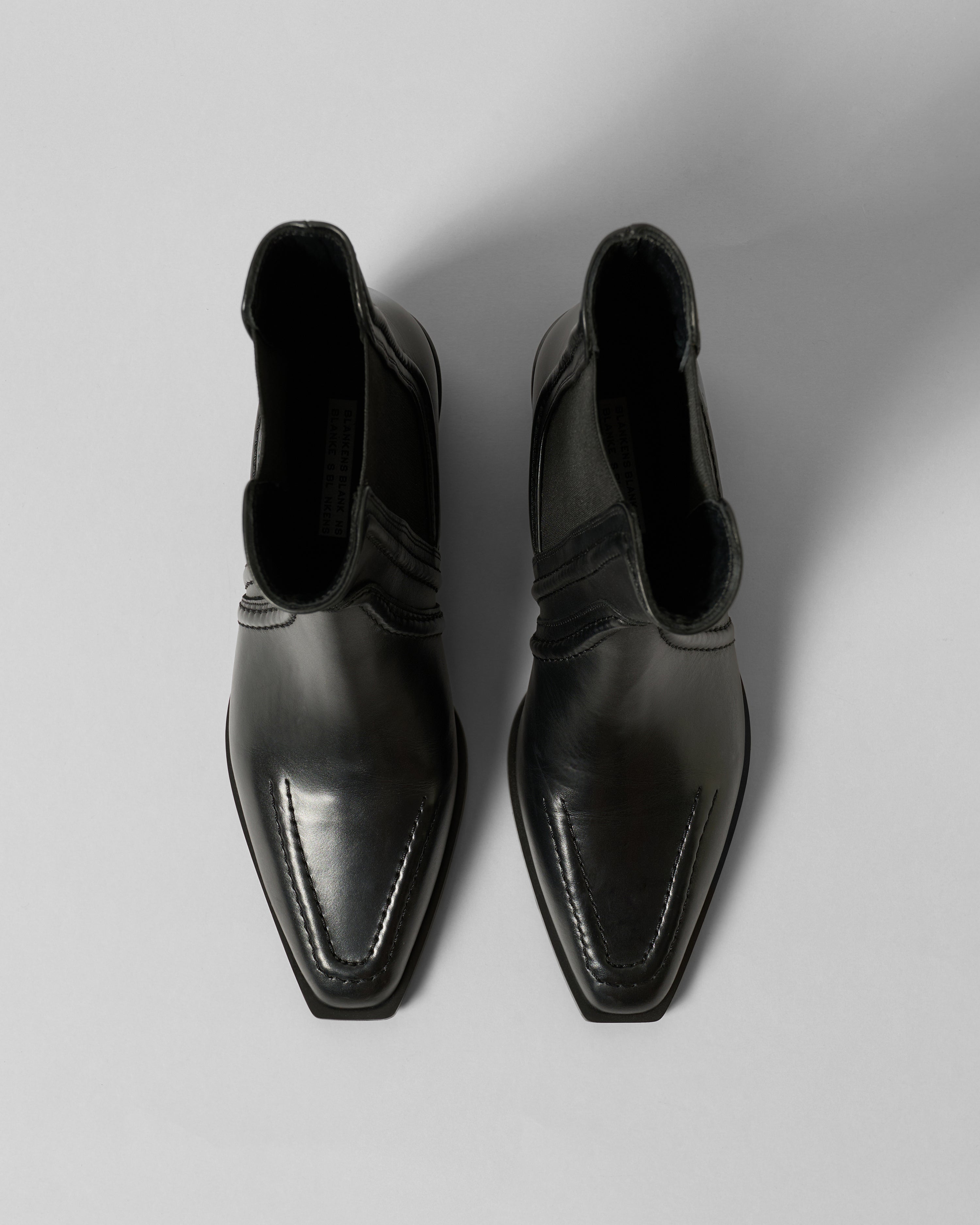 Pair of black leather ankle boots on a light gray background