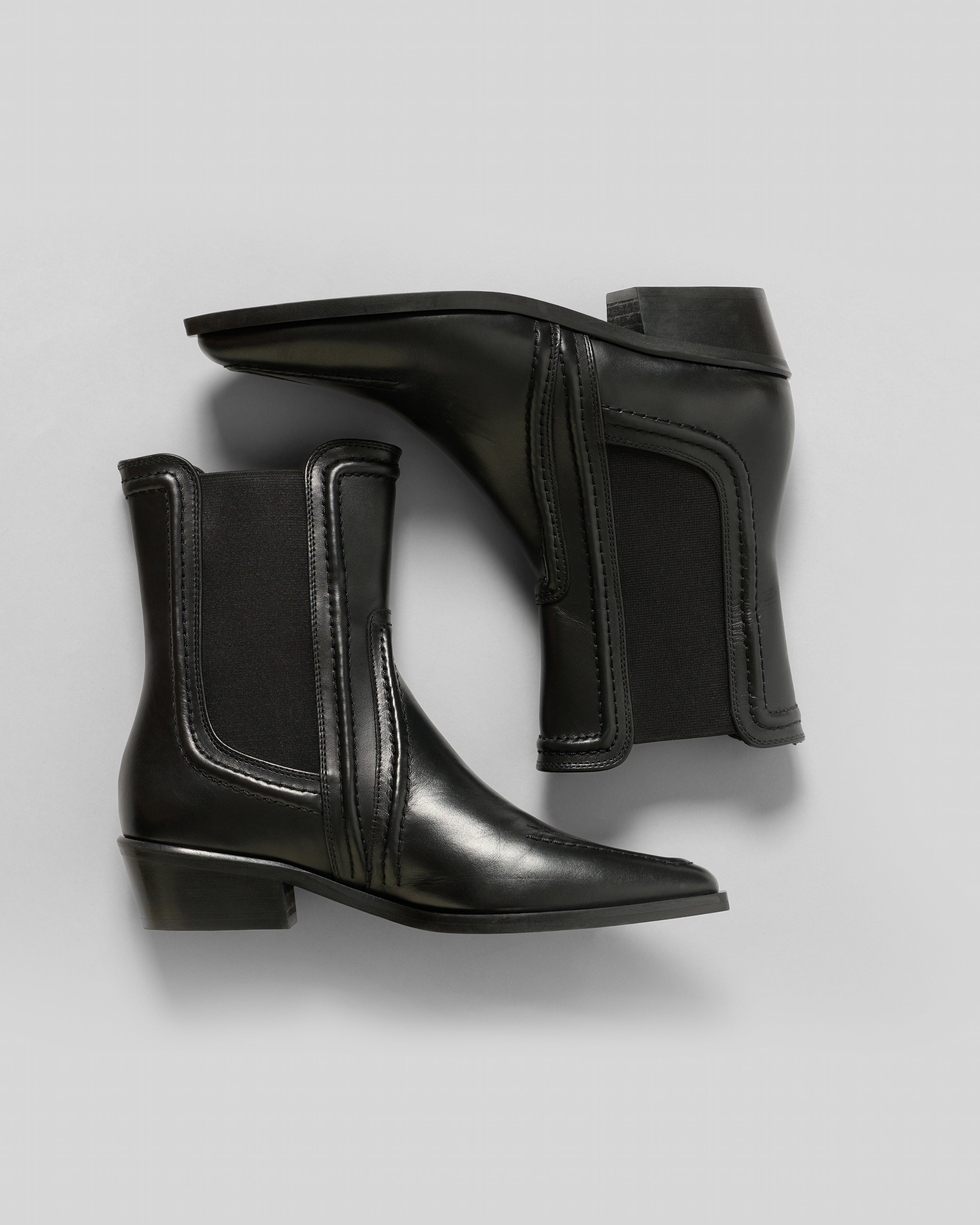 Pair of black leather ankle boots on a light gray background