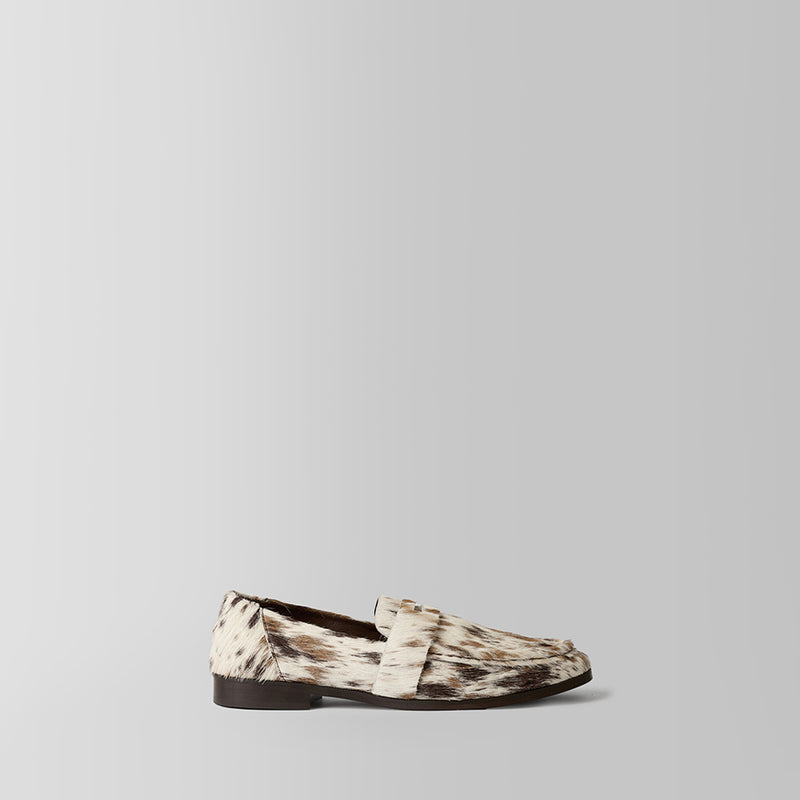 A single loafer in a brown and beige animal print pattern, shown in a side profile against a light gray background.
