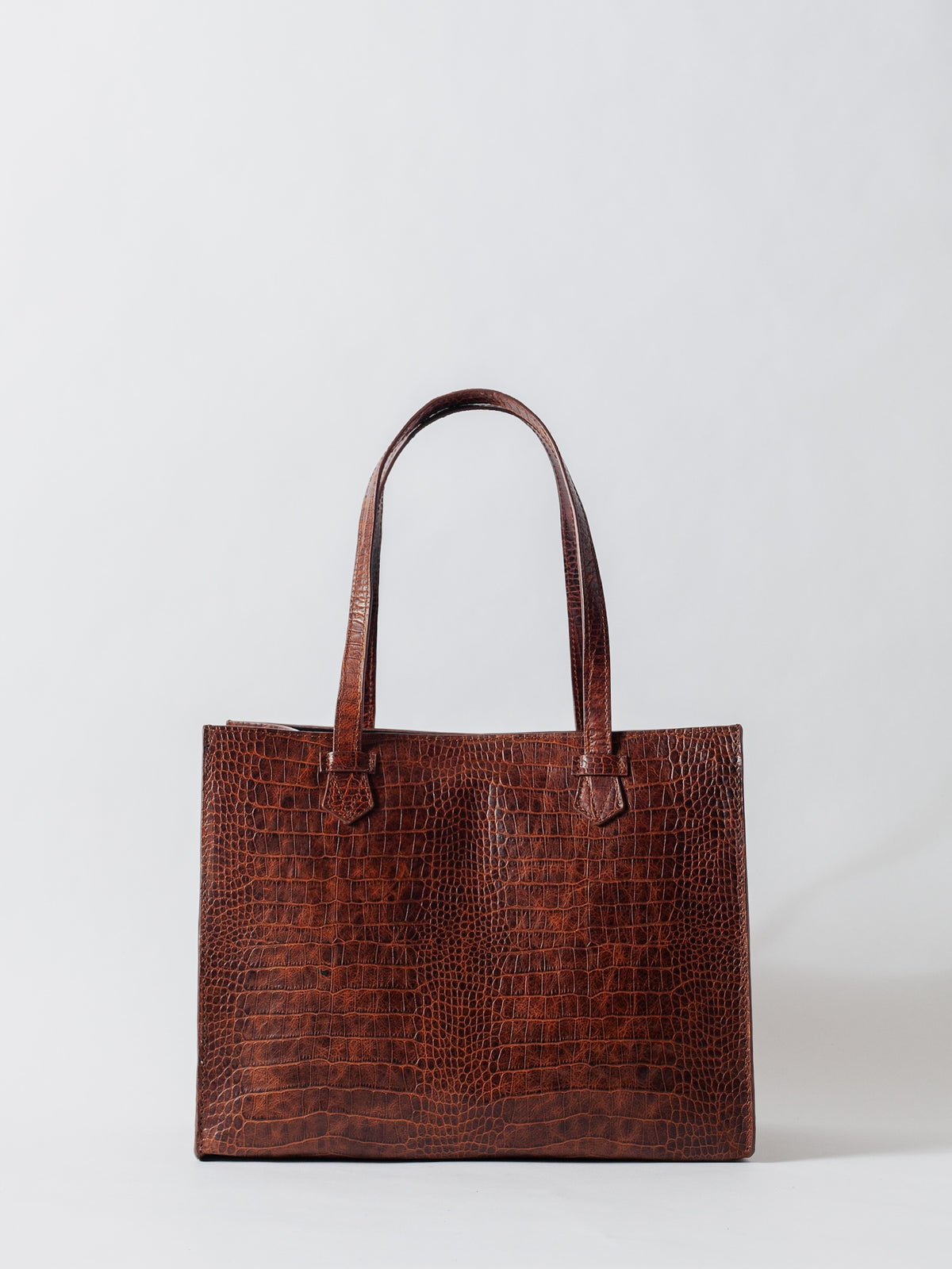 Brown crocodile-patterned tote bag on a light gray background