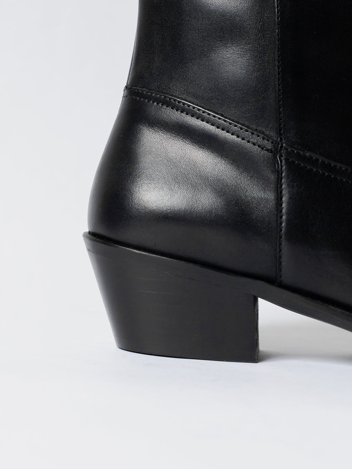 Close-up of a black leather boot on a white background