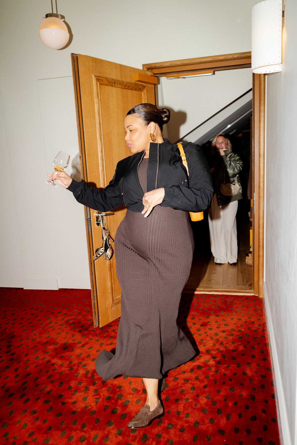 Woman in formal attire holding a glass of wine on a red carpet