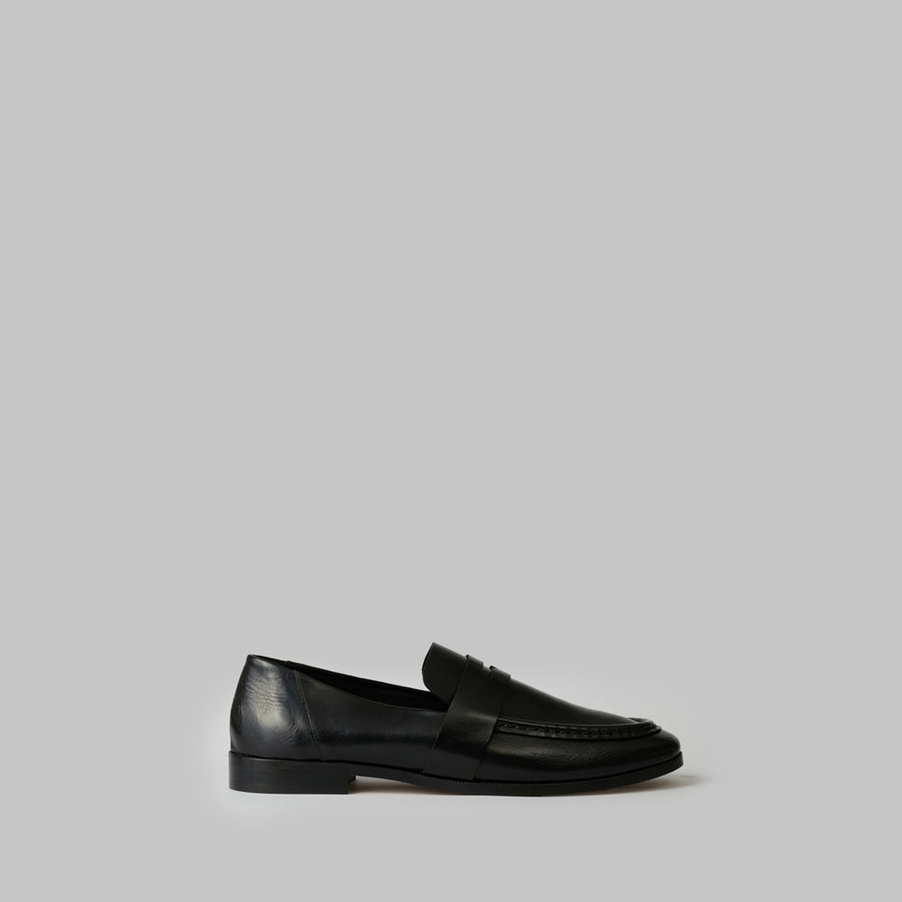 Black loafer with a strap on a white background