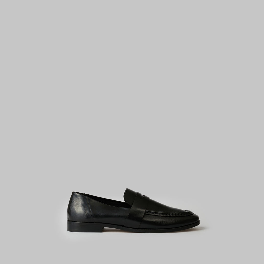 Black loafer with a strap on a white background