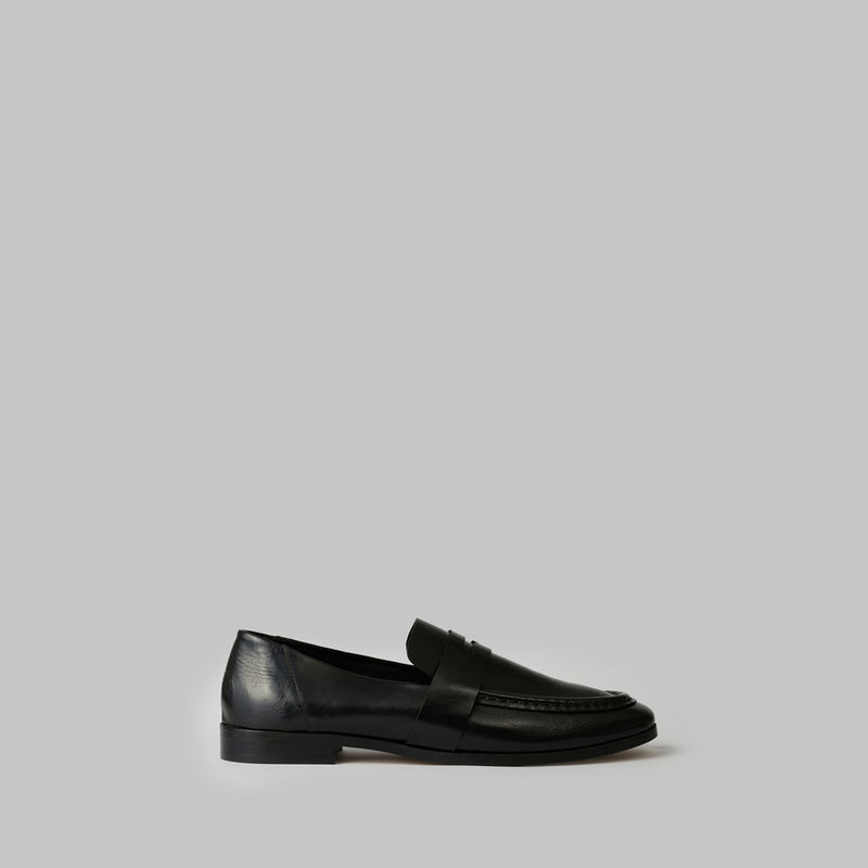 Black loafer with a strap on a white background