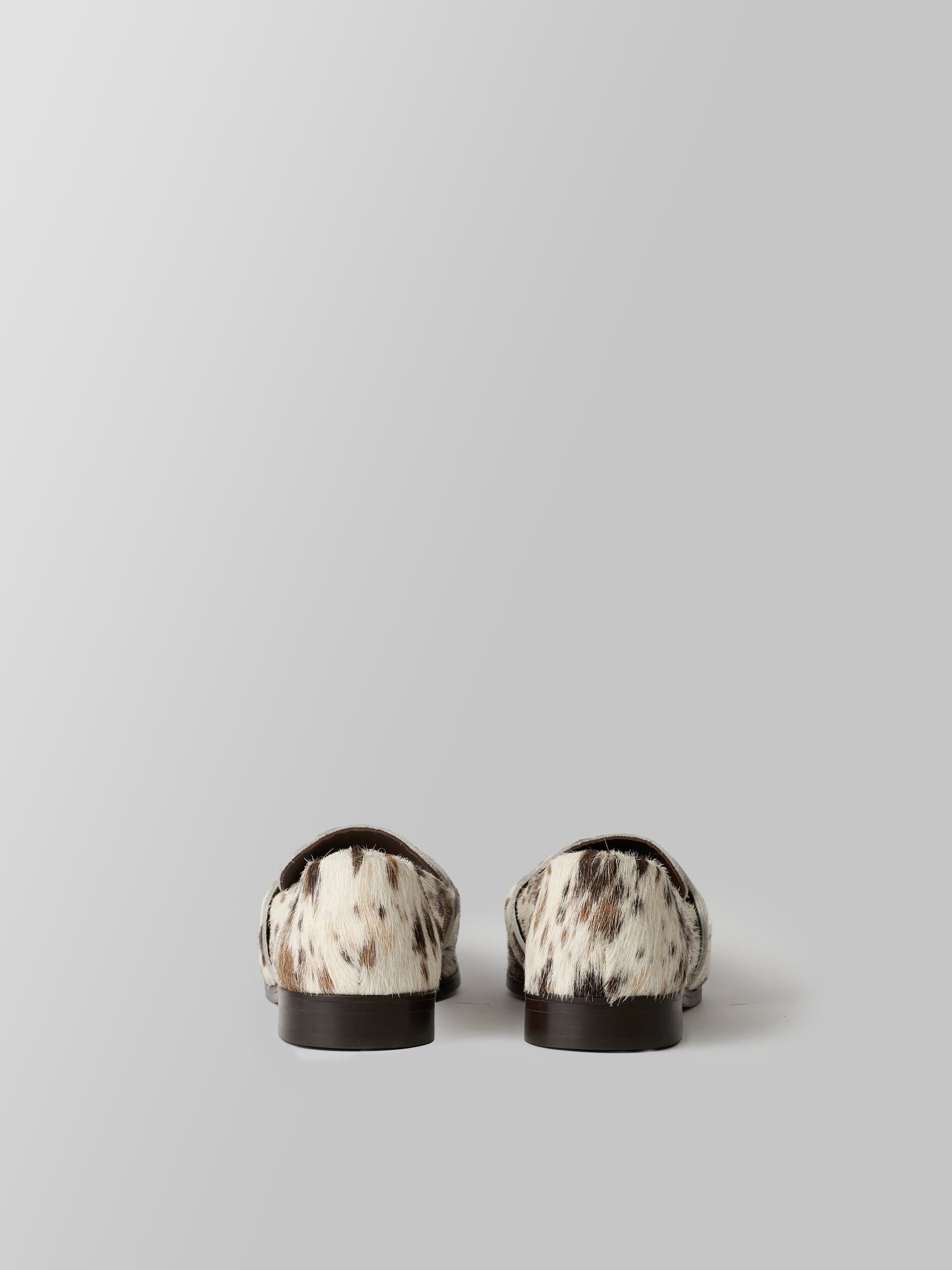 Pair of black and white patterned loafers on a light gray background
