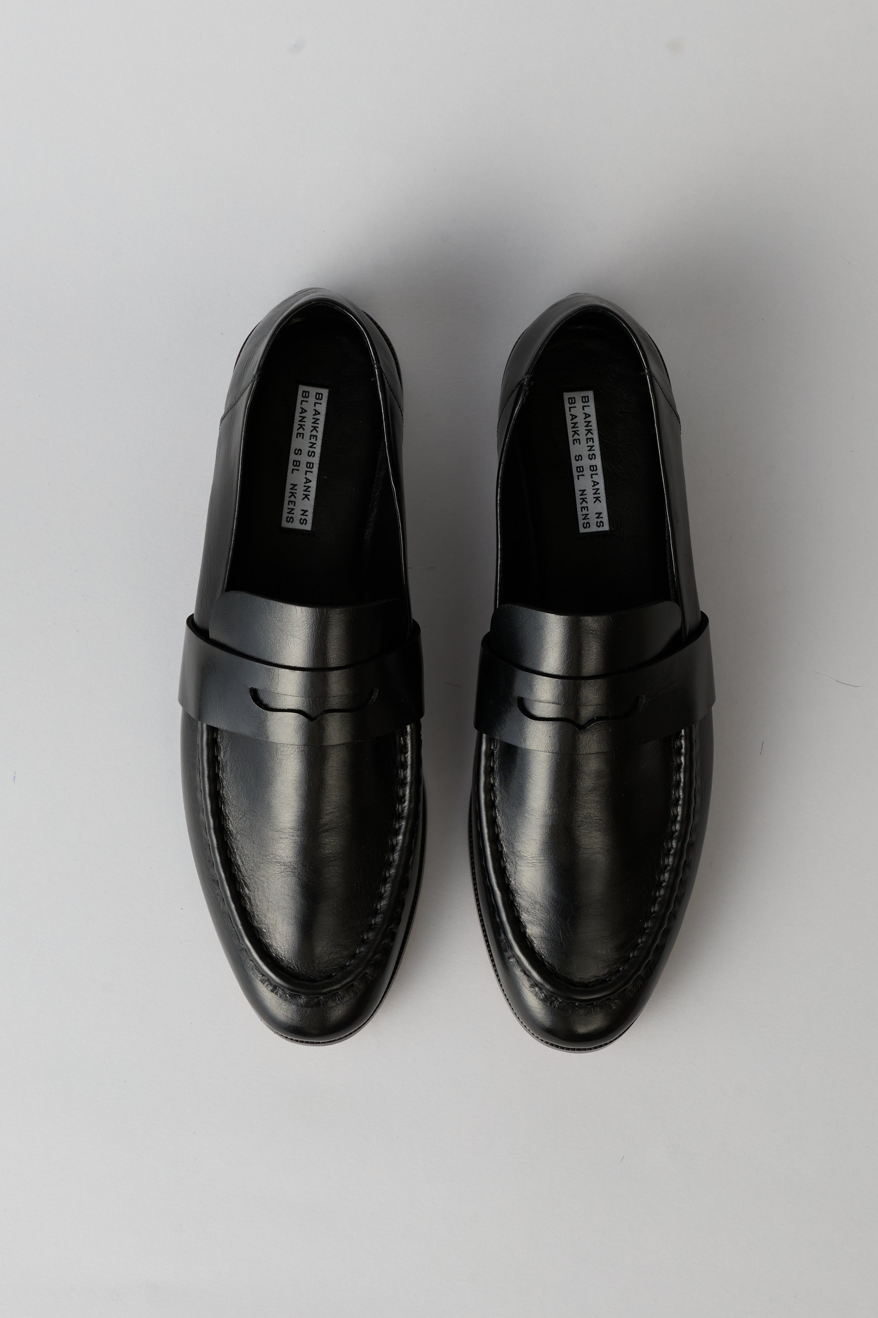 Black loafer with a strap on a white background