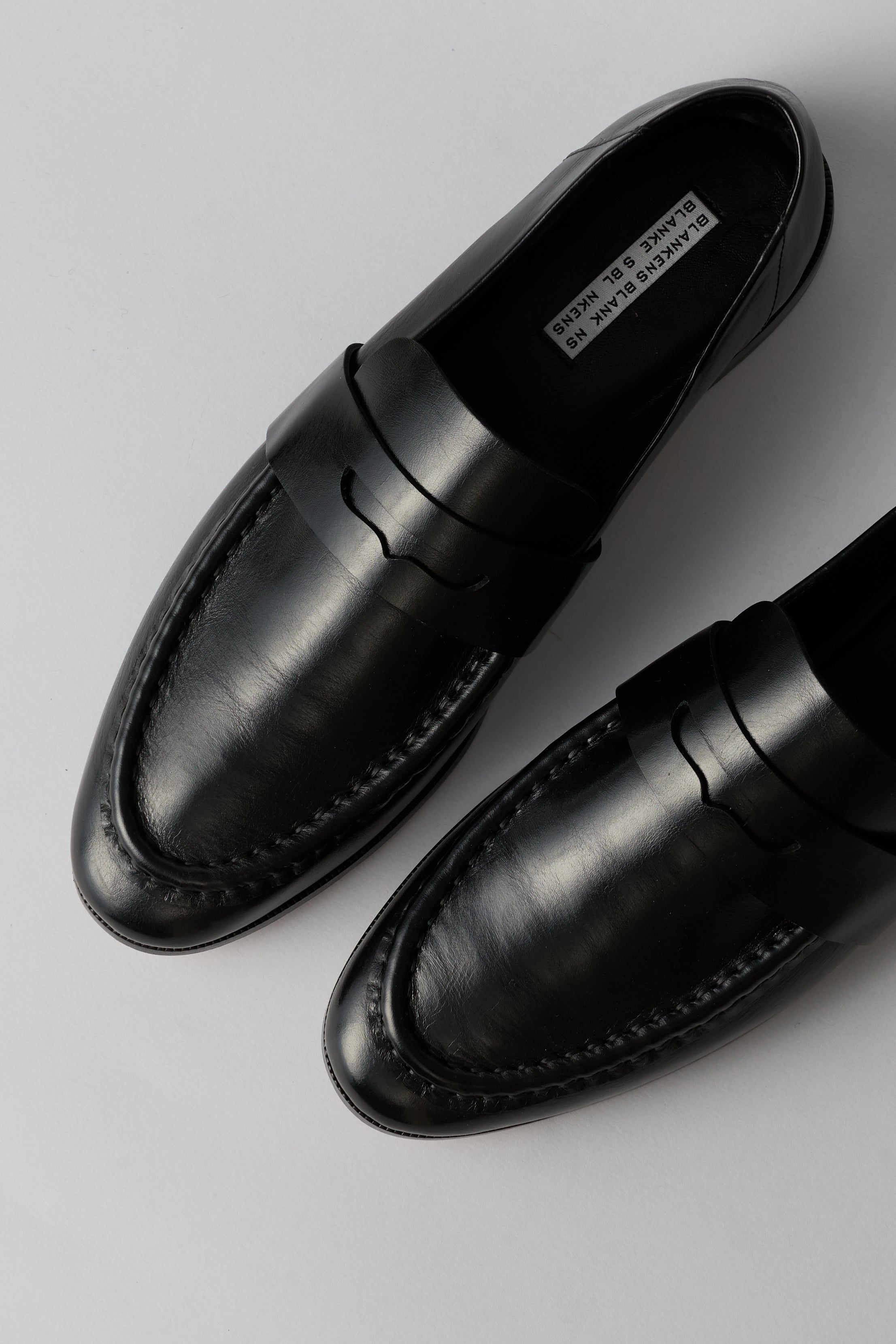 Black loafer with a strap on a white background