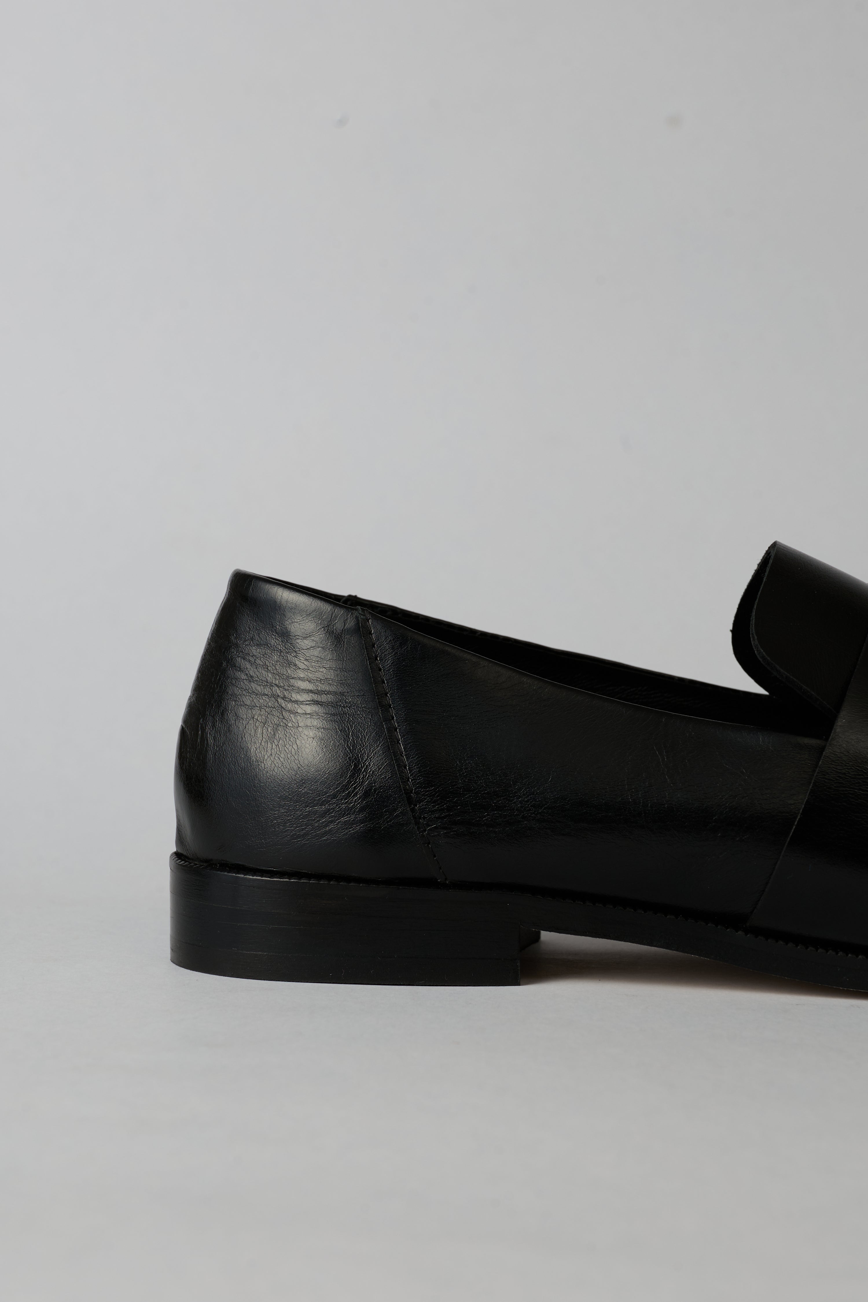 Black loafer with a strap on a white background